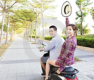 Happy young couple riding scooter in town