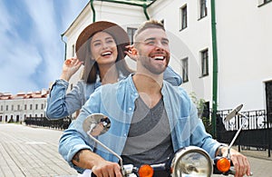 Happy young couple riding scooter in town. Handsome guy and young woman travel. Adventure and vacations concept.