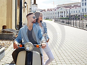 Happy young couple riding scooter in town. Handsome guy and young woman travel. Adventure and vacations concept.