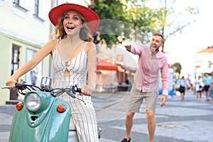 Happy young couple riding scooter in town. Handsome guy and young woman travel. Adventure and vacations concept