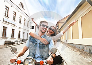 Happy young couple riding scooter in town. Handsome guy and young woman travel. Adventure and vacations concept.