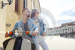 Happy young couple riding scooter in town. Handsome guy and young woman travel. Adventure and vacations concept.