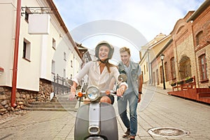 Happy young couple riding scooter in town. Handsome guy and young woman travel. Adventure and vacations concept.