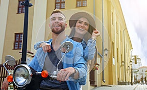 Happy young couple riding scooter in town. Handsome guy and young woman travel. Adventure and vacations concept.