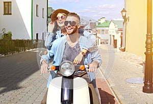 Happy young couple riding scooter in town. Handsome guy and young woman travel. Adventure and vacations concept.