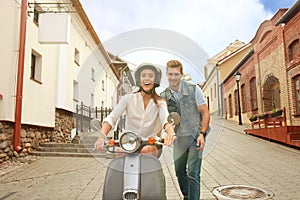 Happy young couple riding scooter in town. Handsome guy and young woman travel. Adventure and vacations concept.