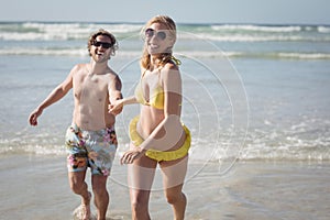 Happy young couple running on shore at beach`