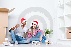 Happy young couple in Santa hats in new house