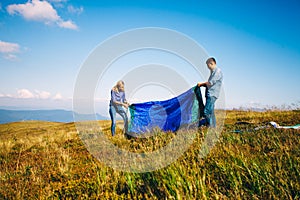 Happy young couple setting a tent in a mountains