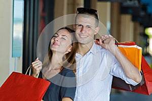 happy young couple with shopping bags in mall