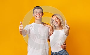 Happy young couple showing thumbs up gesture, recommending something