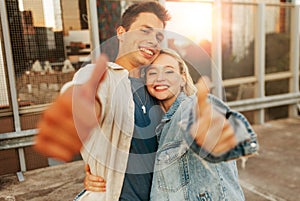 happy young couple showing thumbs up on roof top