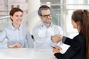 Happy young couple signing mortgage insurance investment contract handshake broker photo