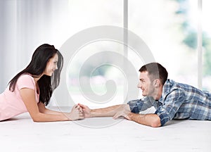 Happy young couple sitting on floor looking up while dreaming their new home and furnishing. Mock up