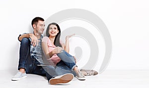 Happy young couple sitting on floor looking up while dreaming their new home and furnishing. Mock up