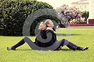 Happy young couple sitting on the grass in city park