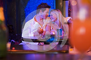 Happy young couple sitting in a nightclub, smiling