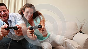 Happy young couple sitting on sofa playing video games
