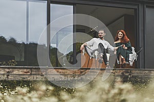 Happy young couple sitting on the terrace of their country house