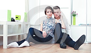 Happy young couple sitting together on the floor