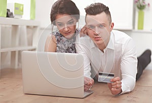 Happy young couple sitting together on the floor with laptop