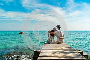 Happy young couple sitting on wood bridge and sea beach at Koh MunNork Island, Rayong, Thailand