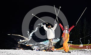 Happy young couple skiing at ski resort at night.