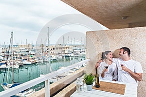 Happy  young couple smiling, drinking red wine on the terrace at the marina. Couple relationship and lifestyle concept
