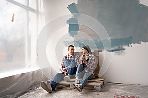 Happy young couple smiling each other while having break during repairment. redecorating and redesigning home