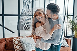 Happy young couple smiling and embracing while bonding together at home