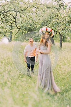 Happy young couple smiling while walking outdoors, woman in wreath foreground blured