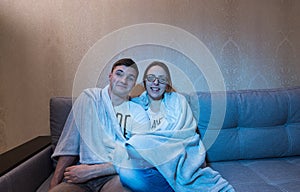 Happy young couple snuggling up watching television and laughing