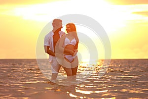 Happy young couple spending time  on sea beach at sunset