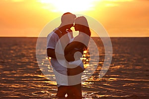 Happy young couple spending time  on sea beach at sunset
