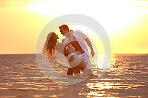 Happy young couple spending time  on sea beach at sunset