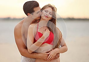 Happy young couple spending time together on  beach at sunset