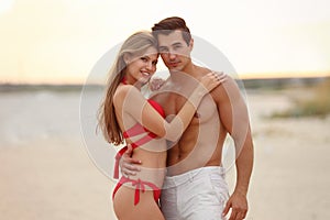 Happy young couple spending time together on  beach at sunset