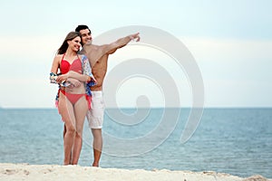 Happy young couple spending time together on sea beach. Space for