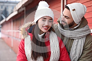 Happy young couple spending time together at winter fair. Christmas celebration