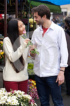 Happy young couple standing by flower shop