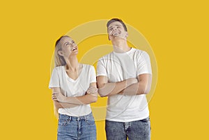 Happy young couple standing isolated on yellow background, looking up and smiling