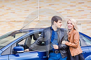 Happy young couple standing near the car