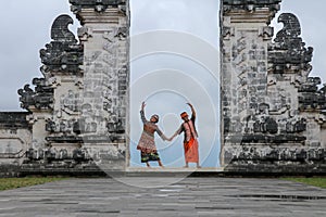 Happy young couple staying in temple gates of heaven and holding hands of each other. Perfect Honeymoon concept. Lempuyang Luhur