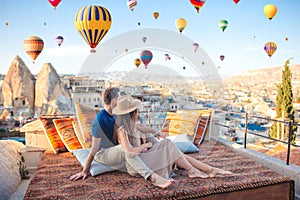 Happy young couple during sunrise watching hot air balloons in Cappadocia, Turkey