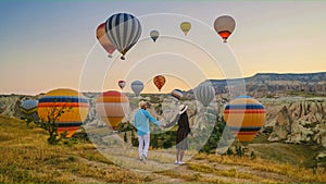 happy young couple during sunrise watching the hot air balloons of Kapadokya Cappadocia Turkey