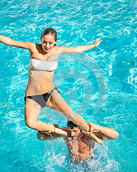 Happy young couple in swimming pool jumping from the shoulder