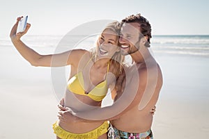 Happy young couple taking selfie at beach