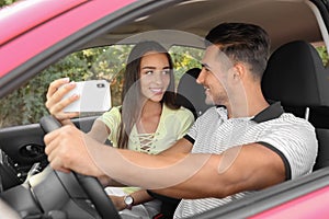 Happy young couple taking selfie in car