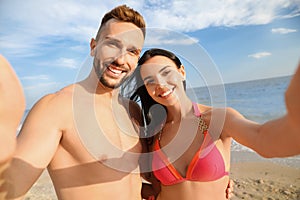 Happy young couple taking selfie on beach