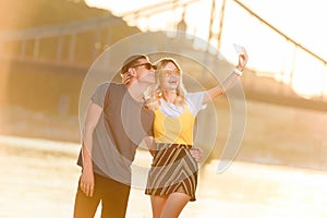 happy young couple taking selfie with smartphone on river beach